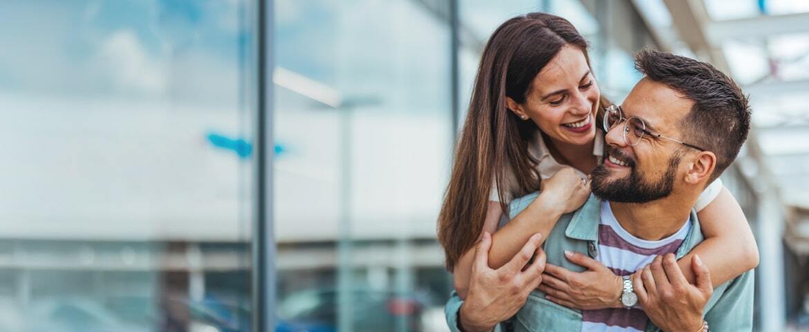 a couple cuddling next to a glass building